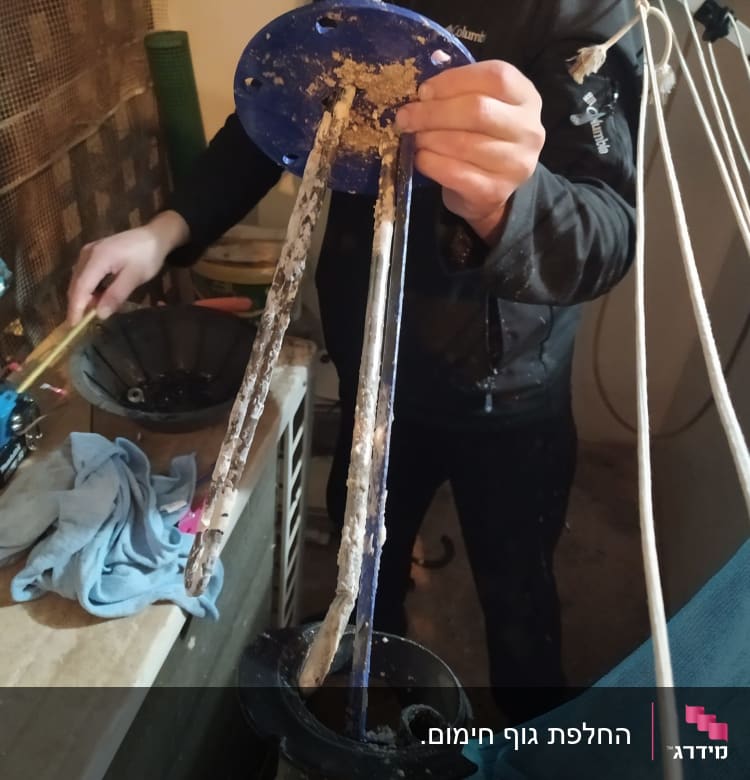 אדם מחזיק חלקי דוד שמש עם אבנית